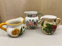 Group shot of three hand-painted ceramic pitchers