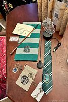Overview of scarf, tie, wand, lamp, pocket watch, coin pouch, keys, chocolate frog keychain, deathly hallows pendant, USB cable, envelope and ticket