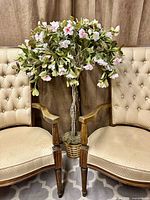 Full view of faux flowering tree between chairs showing overall size and basket planter