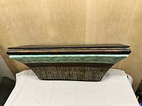Front angled view showing overall form, faux wood top, turquoise band, ribbed base