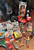 Group shot showing all items including gorilla mask, RC car & controller, bobblehead, plush cat, packaged items, vehicles, figures