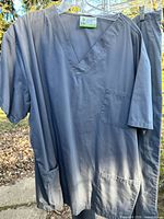 Dark grey Klikfits scrub top with pockets and partial view of matching pants