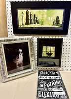 Group shot of three framed prints and packaged metal sign