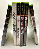 Six Xbox game cases standing showing spines and titles