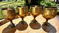 Front view of all four goblets showing shape, etched pattern and patina