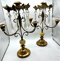 Both brass three-arm candelabras showing overall design and prisms