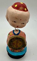 Front view of child figure holding coin medallion