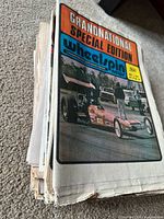 Stack of vintage auto racing newspapers topped by Wheelspin News Grandnational Special Edition
