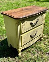 Front and side view showing two drawers, carved details, wood top, distressed paint