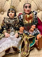 Both puppets seated showing costumes and carved heads