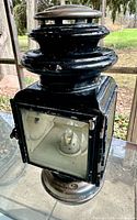 Front view showing glass panel, pedestal base, bulb socket