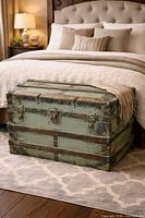 Full view of green domed steamer trunk at foot of bed