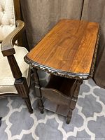 Three-quarter view of table showing carved edge top, turned legs, built-in rack
