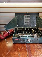 Stove closed with lid open, showing grate and fuel tank beside