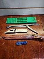 Full lot view with drill bit holder, pliers, fish-shaped utensil, rusted clamp tool, blue cord