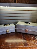 Two closed Umco aluminum tackle boxes side by side