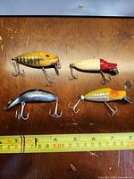 Group shot of four Heddon lures with measuring tape for scale
