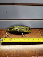 Flatfish T60 lure beside tape measure showing size, two treble hooks visible