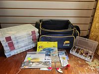 Overall lot showing Plano bag, stack of four boxes, fifth open box with spinnerbaits, packaged tackle on floor