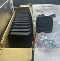 Box showing stacked black plastic bins, separate bin, and bag of hooks