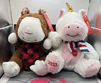 Front view of both plush toys showing tags, badges, embroidered year