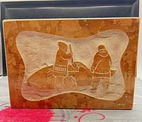 Front view showing carved Inuit scene and signature