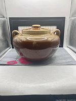 Front view of brown/tan ceramic crock with lid and two handles