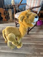 Side view of plush lion marionette standing on floor, strings visible