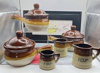 Group shot showing both lidded crocks and two measuring pitchers