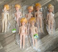 Seven sealed dolls laid out on floor showing overall lot