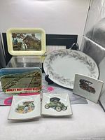 Group view of three square trinket dishes, two rectangular souvenir trays and oval platter