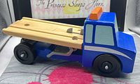 Left front view of blue wooden flatbed tow truck