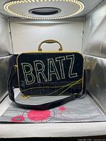 Front of black glitter Bratz case with rhinestone logo and strap