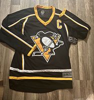 Front view of jersey showing logo, captain patch, hem tag