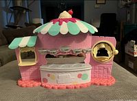 Front angled view of Num Noms playset stand showing canopy, counter and logo