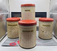 Front view of all four tin canisters showing labels and lids
