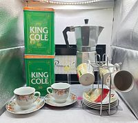 Full lot view: tea tins, espresso maker, espresso cup set on rack, floral teacups and saucers