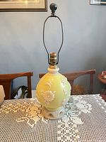 Full view of lamp with harp and finial on lace tablecloth