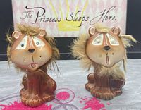 front view of both ceramic lion shakers showing faces, fur, paint wear