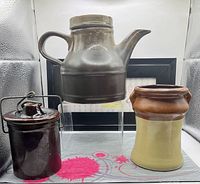 Three pottery items: teapot, lidded jar, two-tone crock