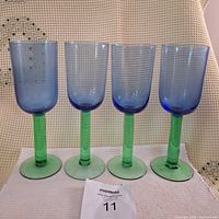 Front view of four blue bowl, green stem Dansk Erika champagne glasses