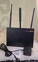 Front view of ASUS AC1900 router with three antennas and power adapter