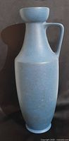 Full front view of tall blue handled ceramic vase