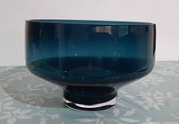 Side view of footed peacock blue glass bowl showing overall form and color