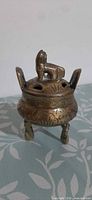 Front view showing brass censer with lid, foo dog finial, three legs