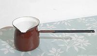 Full view brown enamel pot with white interior and handle