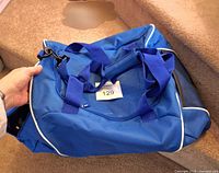 Full view of blue duffel tote bag with carry handles and shoulder strap