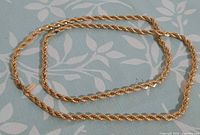 Full view of entire gold-tone rope necklace laid flat
