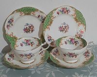 Both trios arranged: cups, saucers, plates showing pattern and condition