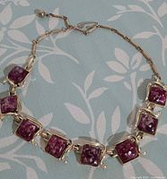 Full view of necklace laid flat showing square purple confetti stones and gold-tone setting